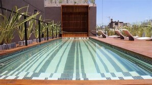 A rooftop swimming pool with a wooden deck, surrounded by potted plants. - Cozy studio in the heart of Recoleta. VLPlaza (CABA)