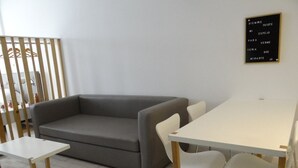 A modern living room with a grey sofa, a white table, and two white chairs. - Cozy studio in the heart of Recoleta. VLPlaza (CABA)
