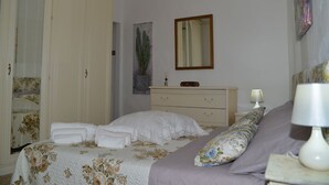 Ein Schlafzimmer mit Bett, Schminktisch, Nachttisch, Lampe und Spiegel.