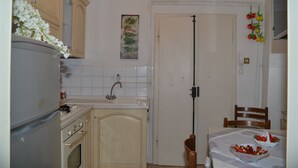 Eine kleine Küche mit Spüle, Herd und Schränken. Eine Tür ist mit einer hängenden Pflanze und einem Telefon an der Wand versehen.