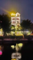 Un hotel con un cartel llamativo, una estructura similar a una torre y su reflejo en el agua.