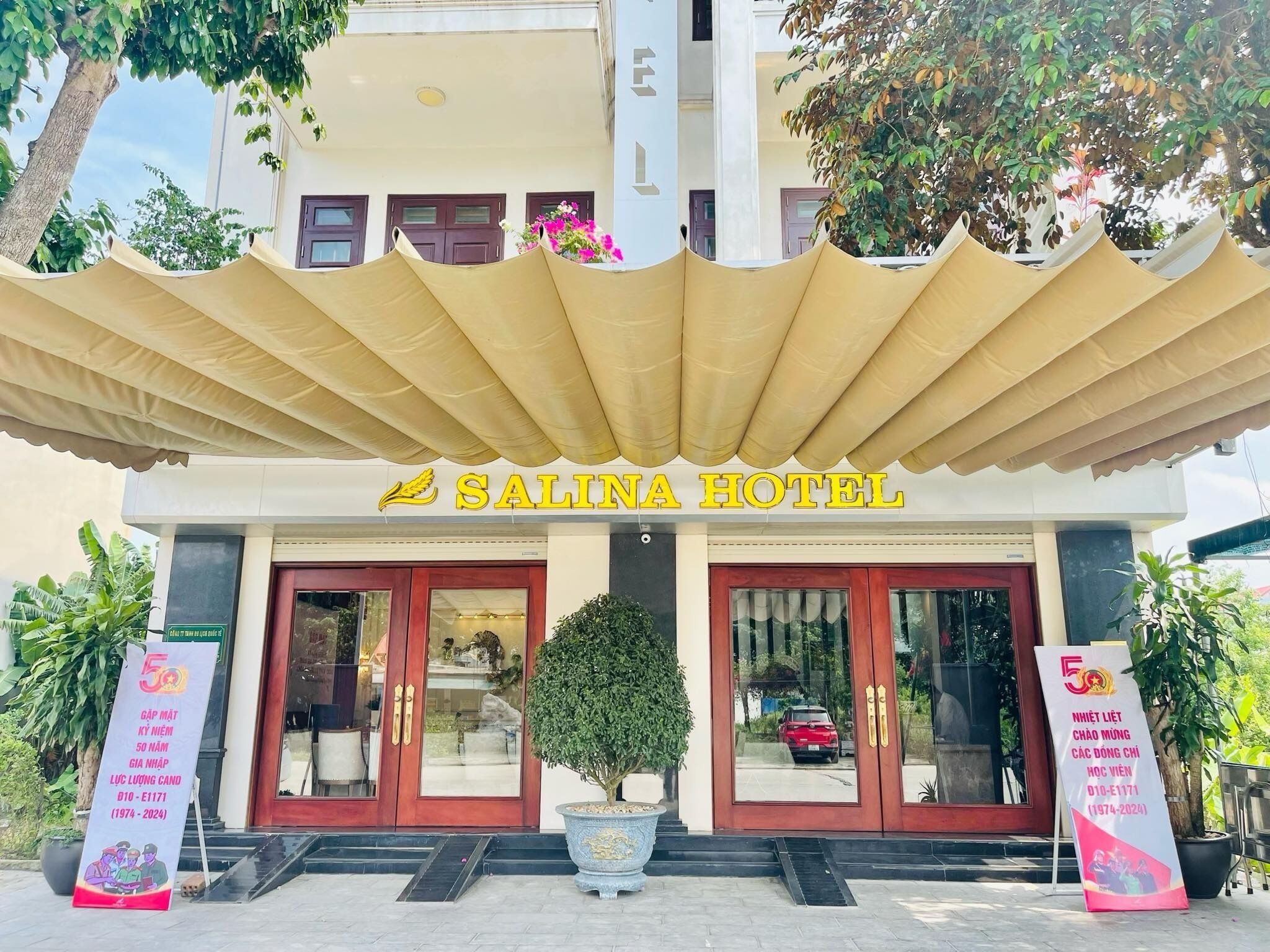 The exterior of Salina Hotel with a large canopy, two main entrances, and a potted plant in front.