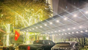 Un área de estacionamiento con varios vehículos, incluyendo una camioneta pickup y un sedán, bajo una estructura cubierta con luces colgantes.