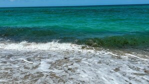 Ein Strand mit klarem türkisblauem Wasser und sanften Wellen.