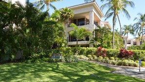 Un hotel con césped cuidado, palmeras y un letrero que indica el nombre 'Banyan Tower'.