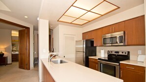 Una cocina moderna con armarios de madera, electrodomésticos de acero inoxidable, una isla grande con un fregadero y una lámpara en el techo.