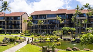 Een hotel met meerdere verdiepingen, buiten zitgedeeltes en een aangelegde tuin met een vijver.