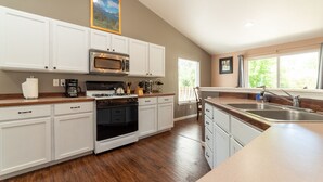 A kitchen with white cabinets, a stainless steel microwave, a gas stove, and a wooden countertop. - Furnished 30+ day rental close to Old Mill! Dog Friendly! (Bend)