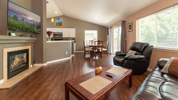 A spacious living room with a fireplace, a dining area, and a kitchen in the background. - Furnished 30+ day rental close to Old Mill! Dog Friendly! (Bend)