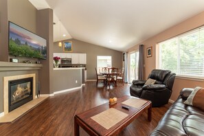 Ein geräumiges Wohnzimmer mit Kamin, Essbereich und einer Küche im Hintergrund.
