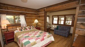 Une chambre située dans un chalet en rondins, avec un lit, deux tables de chevet, une chaise et une fenêtre.