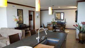 Cocina moderna con una isla central, comedor con sillas y un espejo grande sobre el lavabo.