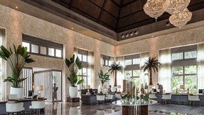 A spacious lobby with a high ceiling, large windows, and multiple seating areas.