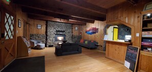 Ein gemütliches Zimmer mit Kamin aus Stein, einer Couch und einem hölzernen Empfangstresen.