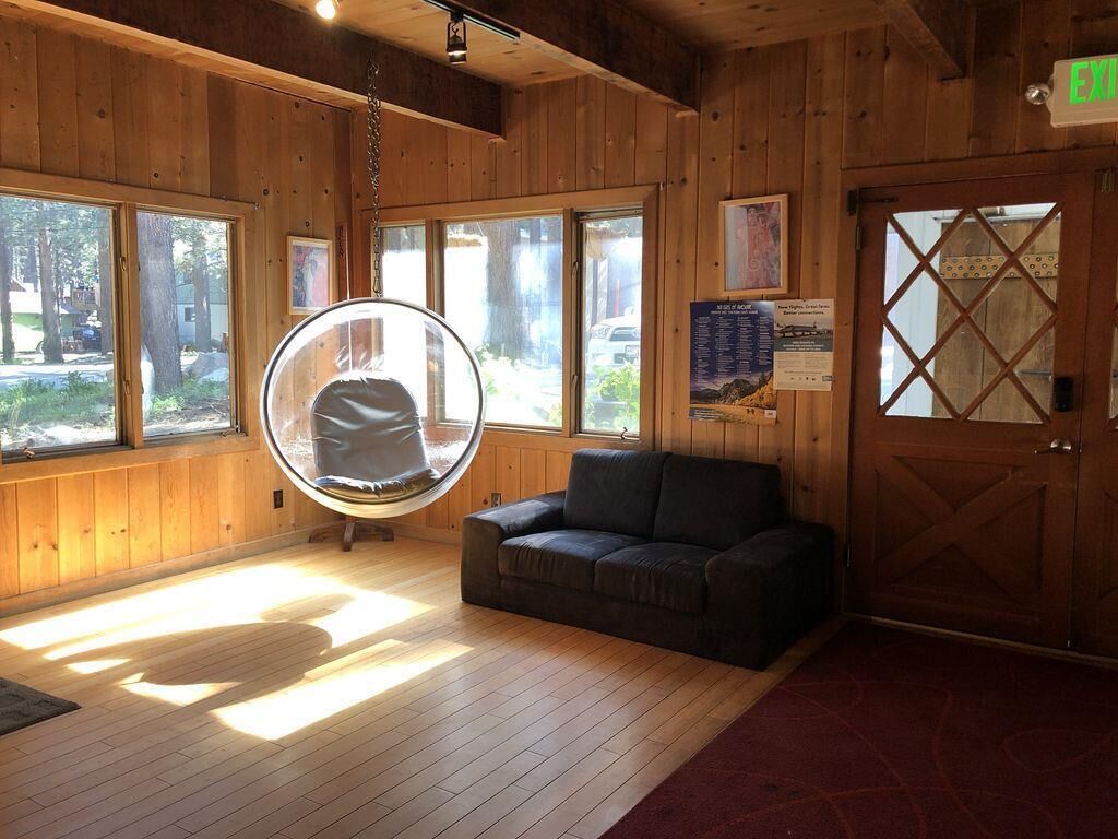 A room with a hanging chair, a sofa, and a door with a sign.