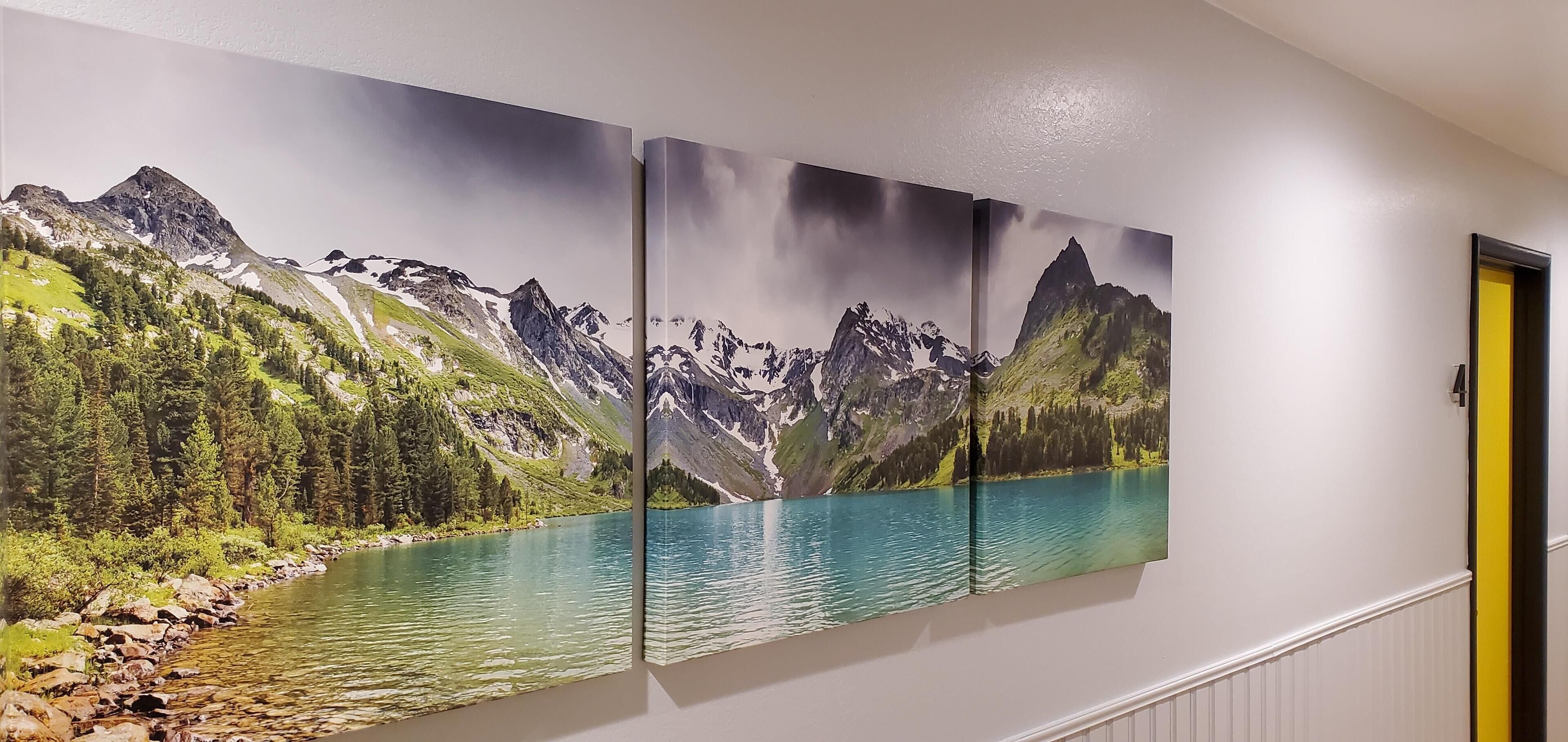 A hallway with a large landscape painting of a mountain lake.