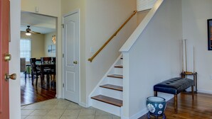 Un escalier avec des marches en bois et une rampe, menant à un espace repas comprenant une table et des chaises.
