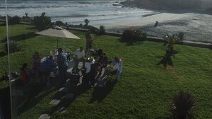 A view of a coastal area with a grassy lawn, a beach, and a rocky outcrop. - Oceanfront Brand New Unit at La Jolla Excellence
The Pelican  (Playa Encantada)