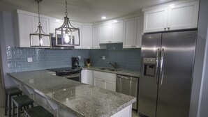 A modern kitchen with granite countertops, stainless steel appliances, and white cabinetry. - Oceanfront Brand New Unit at La Jolla Excellence
The Pelican  (Playa Encantada)