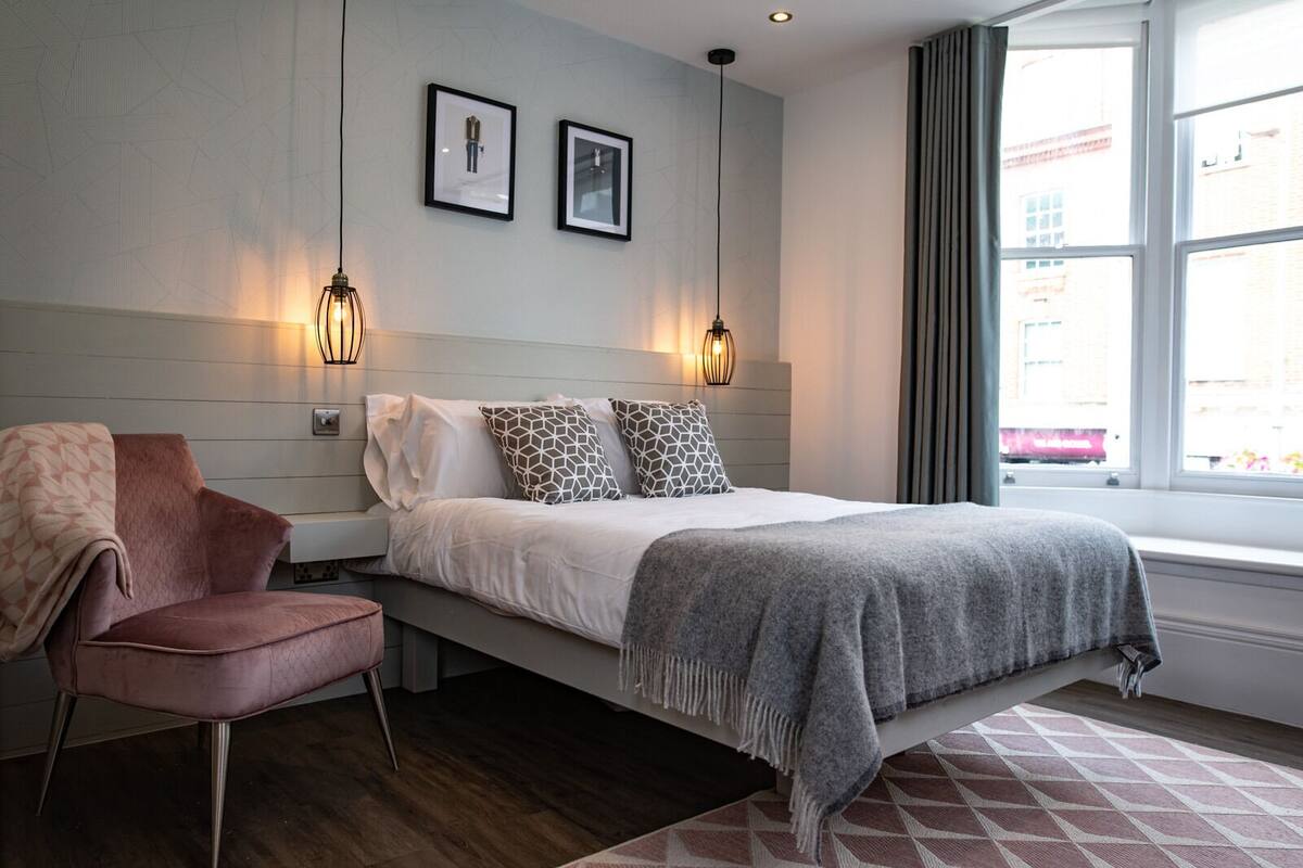 Un dormitorio moderno con cama, una silla y dos luces fijadas a la pared.