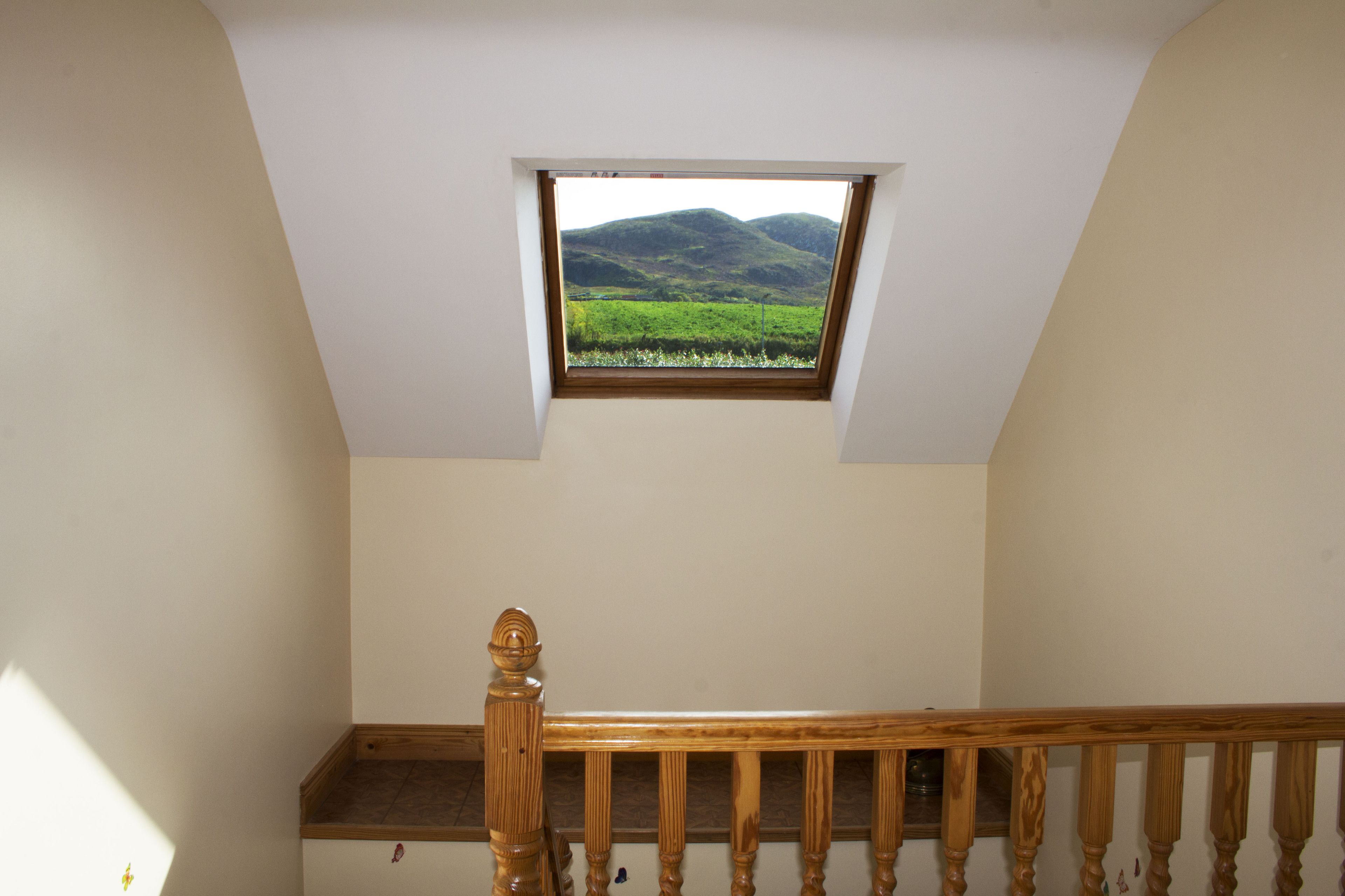 Ein Zimmer mit Dachfenster und Blick auf eine grüne Landschaft.