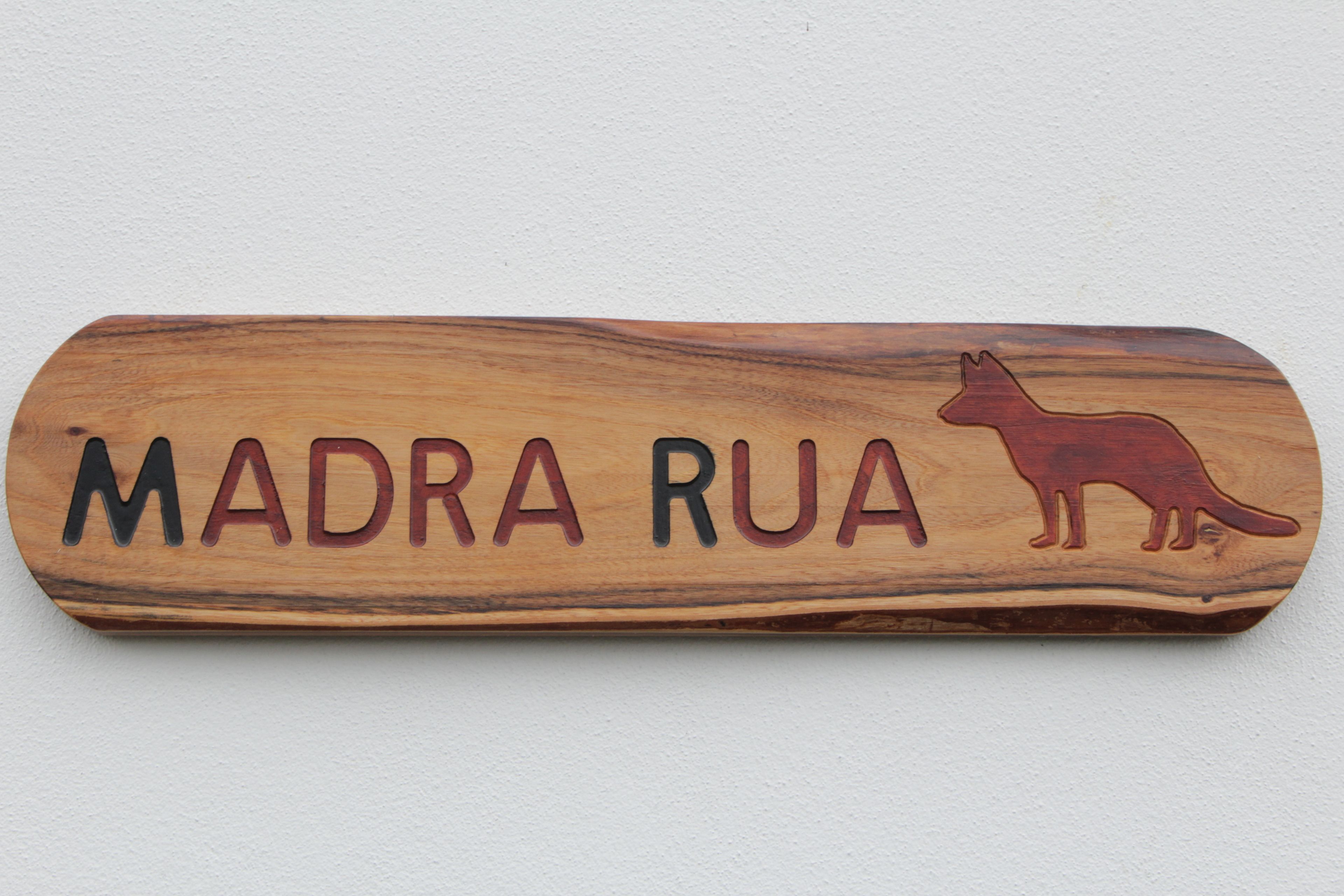 A wooden plaque with the text "MADRA RUA" and a fox silhouette.