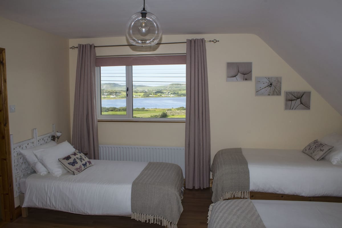 A bedroom with two beds, a view of a lake, and three wall art pieces.