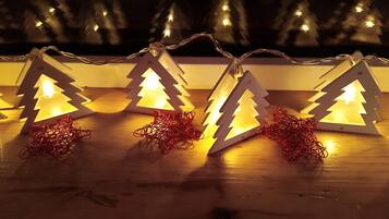 A row of illuminated Christmas tree-shaped lanterns on a wooden surface.