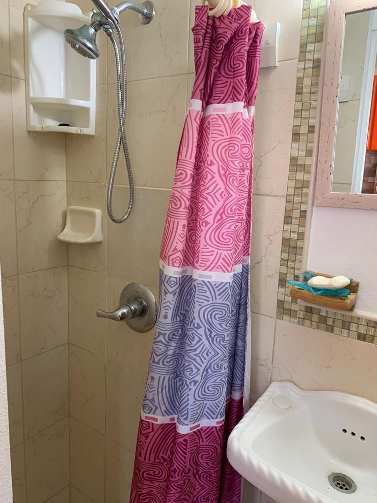 Un bagno con doccia, lavandino e specchio.