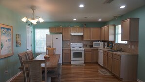 Une cuisine avec des meubles de rangement en bois, une cuisinière blanche et une table à manger avec des chaises.