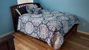 Une chambre à coucher avec un lit, une tête de lit en bois et une fenêtre avec des stores.