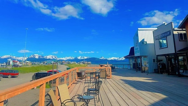 A wooden deck with outdoor seating overlooking a mountainous landscape.