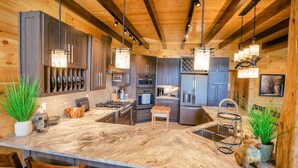 A modern kitchen with a central island, wooden cabinets, and pendant lighting.