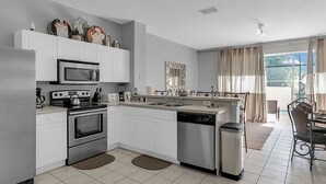 Una cocina moderna con armarios blancos, electrodomésticos de acero inoxidable y lavavajillas.