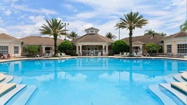 Una piscina con sillones de descanso y palmeras.