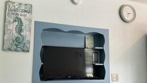 Een tv aan de muur, met een flatscreen en een boek getiteld 'A Journey to Cape Cod' erboven.