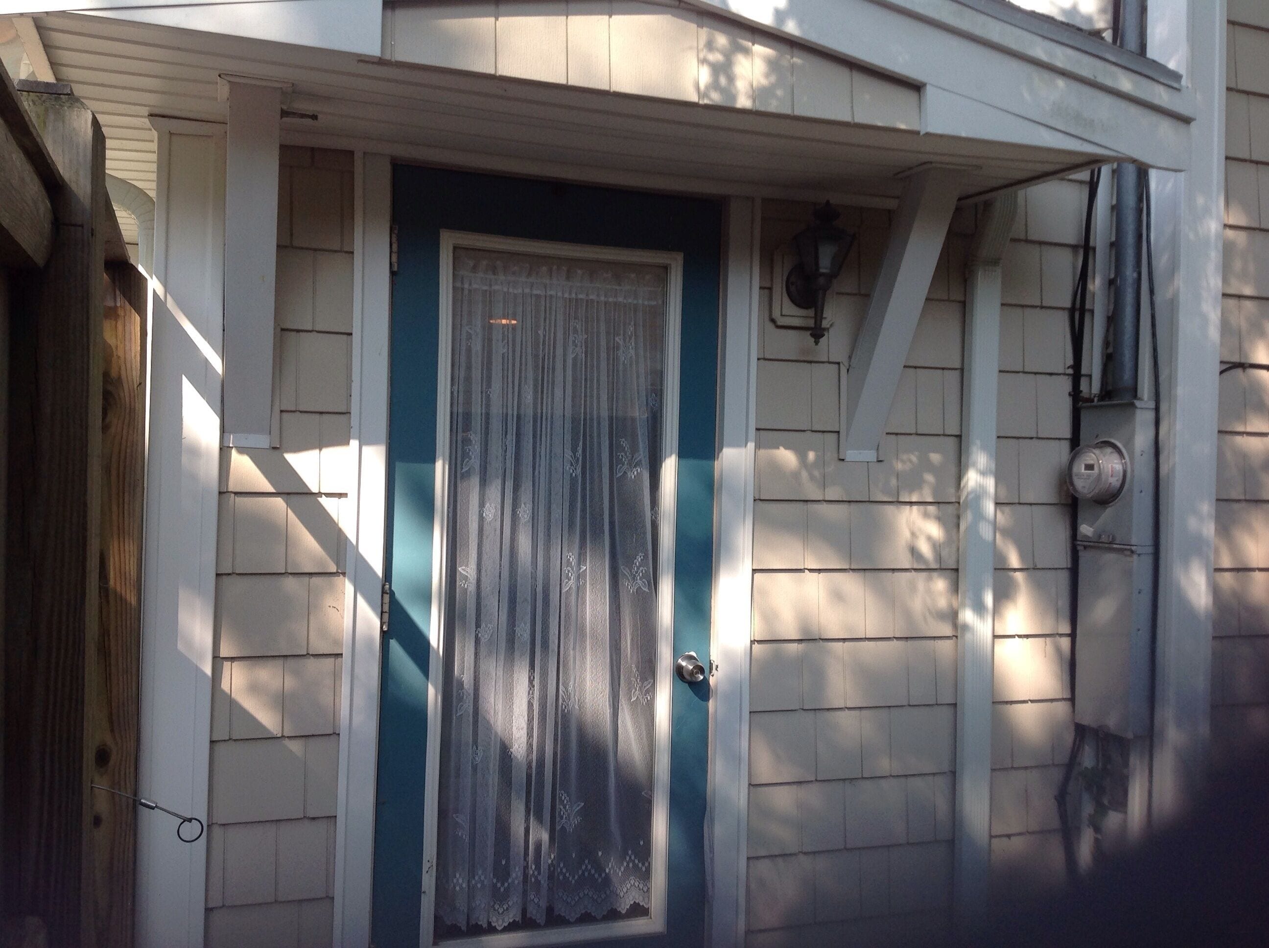 A house with a blue door, white siding, and a small porch.