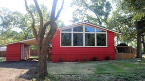 Una casa de un solo piso de color rojo, con un ventanal grande y un porche cubierto.