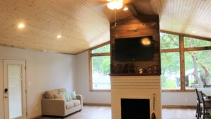 Una sala de estar con chimenea, un sofá y un televisor montado en la pared.