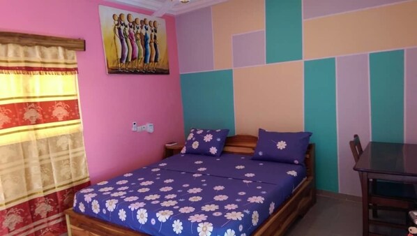 A bedroom with a bed, a nightstand, a table, and a chair.