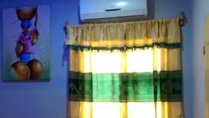 A room with a patterned curtain, an air conditioning unit, and a ceiling fan. - Orchidée Hôtel (Kpalimé)