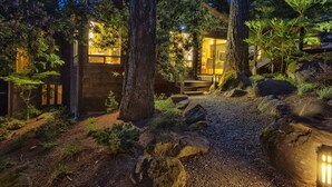 A rustic cabin with a stone exterior, surrounded by trees and a gravel path leading to a wooden deck. - Wine Country Redwood Estate in the Heart of Wine Country (Santa Rosa)