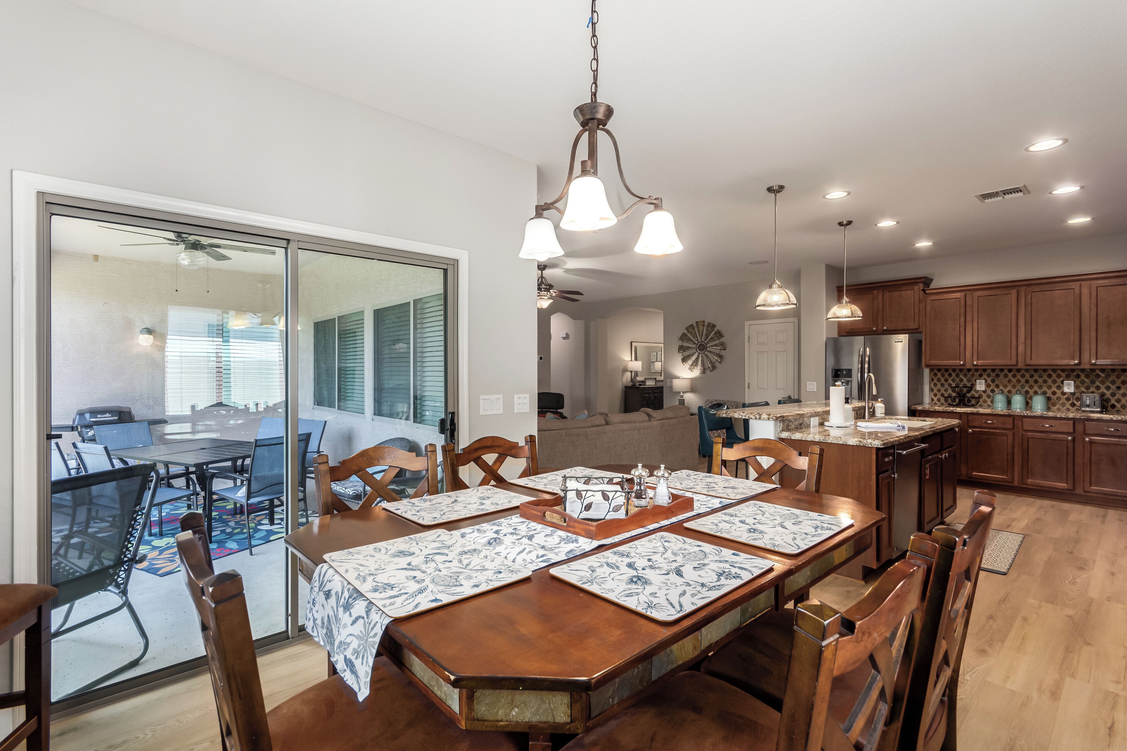 A spacious dining area with a wooden table set for four, a kitchen with wooden cabinets, and a sliding glass door leading to an outdoor patio.