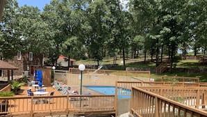 Un patio trasero con piscina, sillas de deck y una valla de madera.