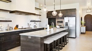 A modern kitchen with a large island, stainless steel appliances, and pendant lighting. - Arcadia 30 | PAC-MAN * Asteroids Arcade * Games * Balcony Views * Resort Ameniti (Santa Clara)