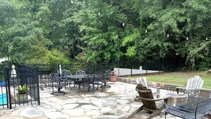 An outdoor patio with stone flooring, metal furniture, and a pool. - Home with lots of space for everyone on a quiet street in 5 points with pool! (Athens)