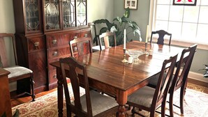 A dining room with a wooden table, chairs, a chandelier, and a large cabinet with glass doors. - Home with lots of space for everyone on a quiet street in 5 points with pool! (Athens)