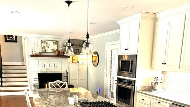 A kitchen with a central island, white cabinetry, stainless steel appliances, and a wooden floor. - Home with lots of space for everyone on a quiet street in 5 points with pool! (Athens)