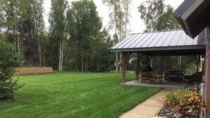 A well-maintained lawn with a patio area featuring outdoor furniture and a pergola. - Spacious Talkeetna home on Ruth Glacier Avenue (Talkeetna)