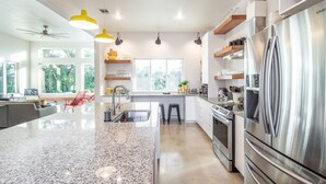 Une cuisine moderne dotée d’un îlot central, d’appareils électroménagers en acier inoxydable et d’un éclairage décoratif lumineux.